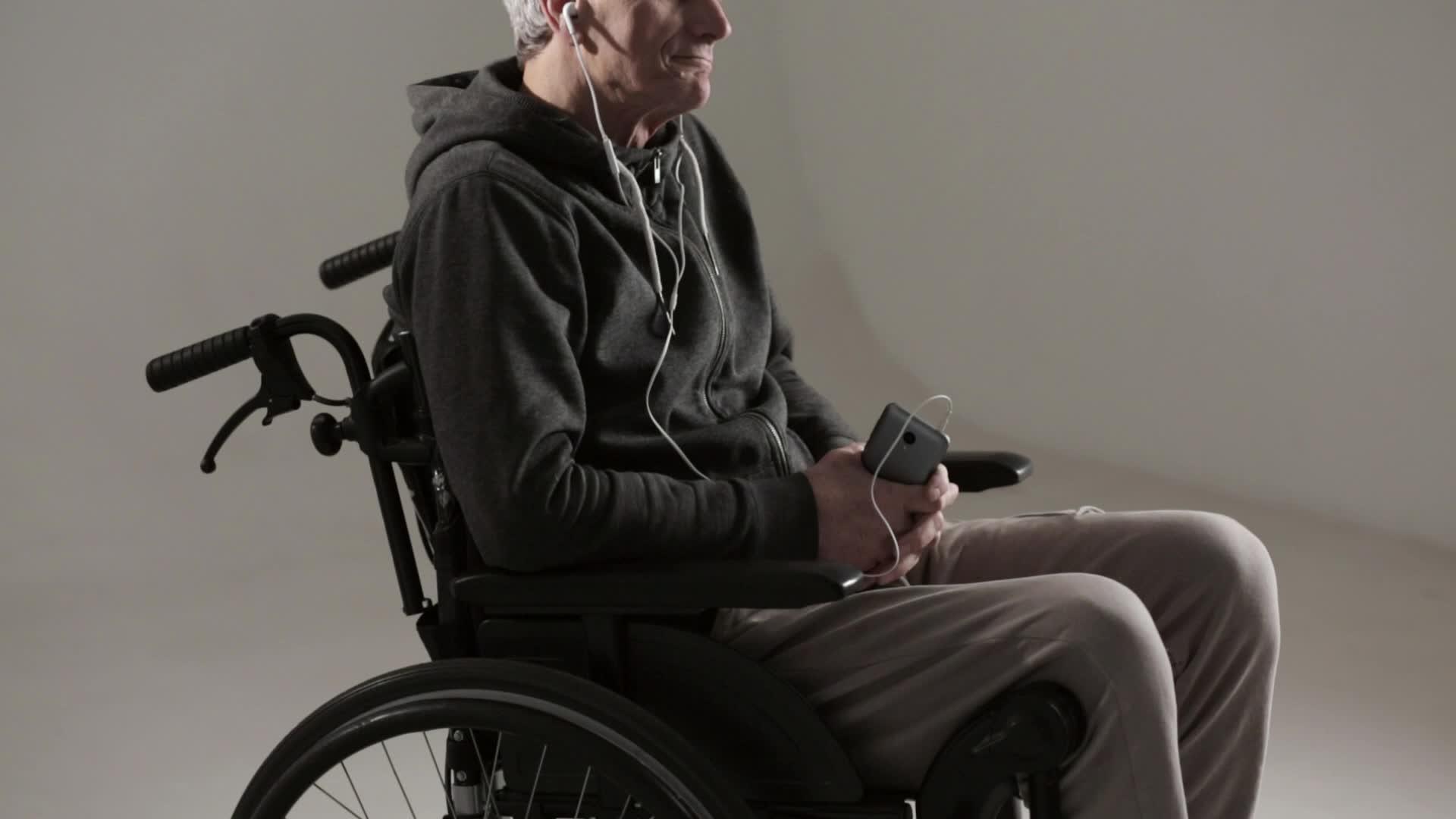 一个坐在轮椅上的灰色头发用耳机听他最喜欢的音乐视频的预览图