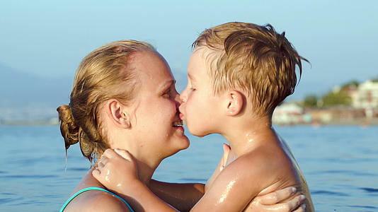 男孩在海里亲吻拥抱他的母亲视频的预览图