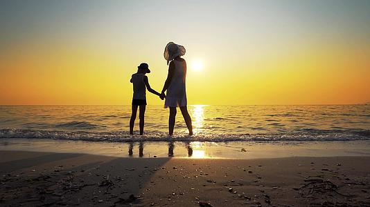 看着夕阳旅行的概念在海滩上赤脚站着戴着帽子视频的预览图