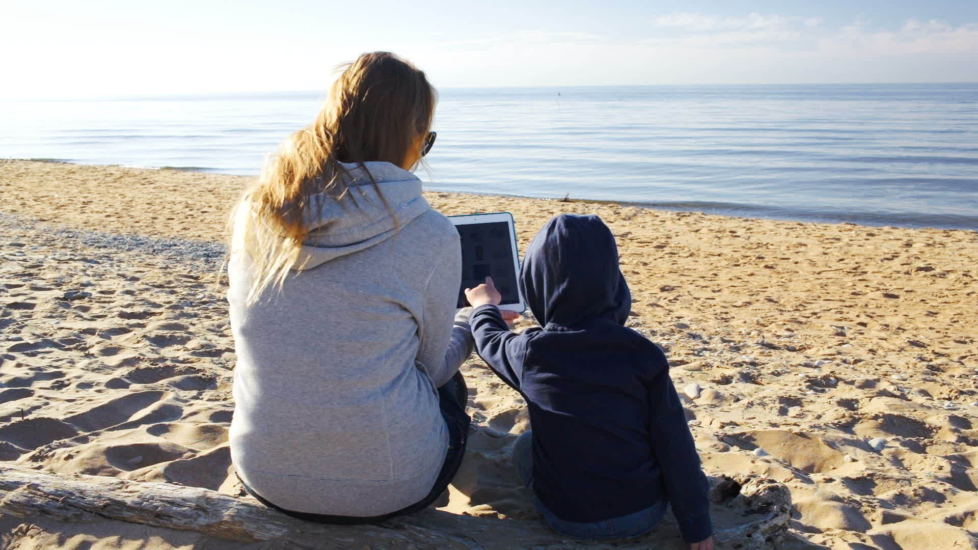 母亲和儿子在海滩上使用平板电脑视频的预览图