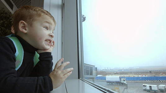 母亲和儿子花时间在机场看窗外的窗户视频的预览图