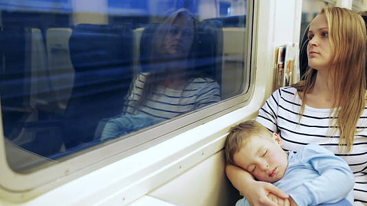 女人看着火车窗外的女人和她的儿子睡在大腿上视频的预览图
