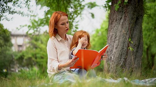 母亲和女孩坐在树下看书视频的预览图