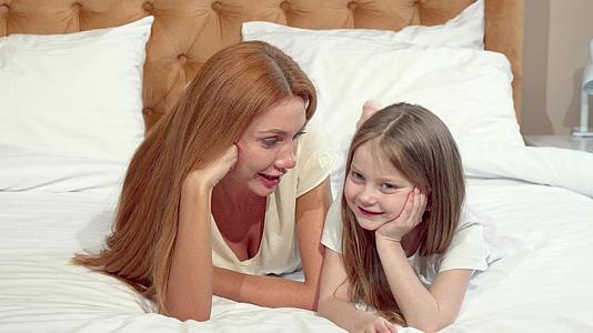 母亲和女儿躺在床上对着镜头微笑视频的预览图