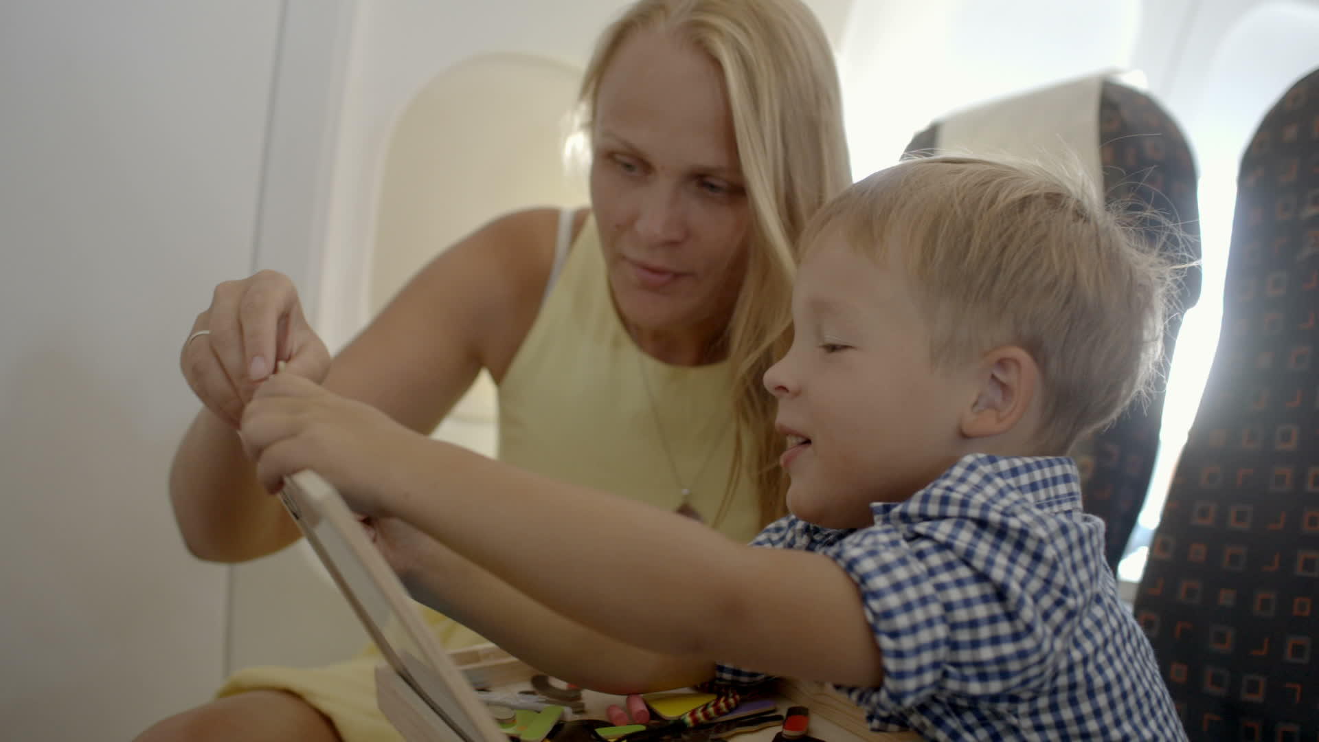 母亲和儿子在飞机上玩游戏视频的预览图