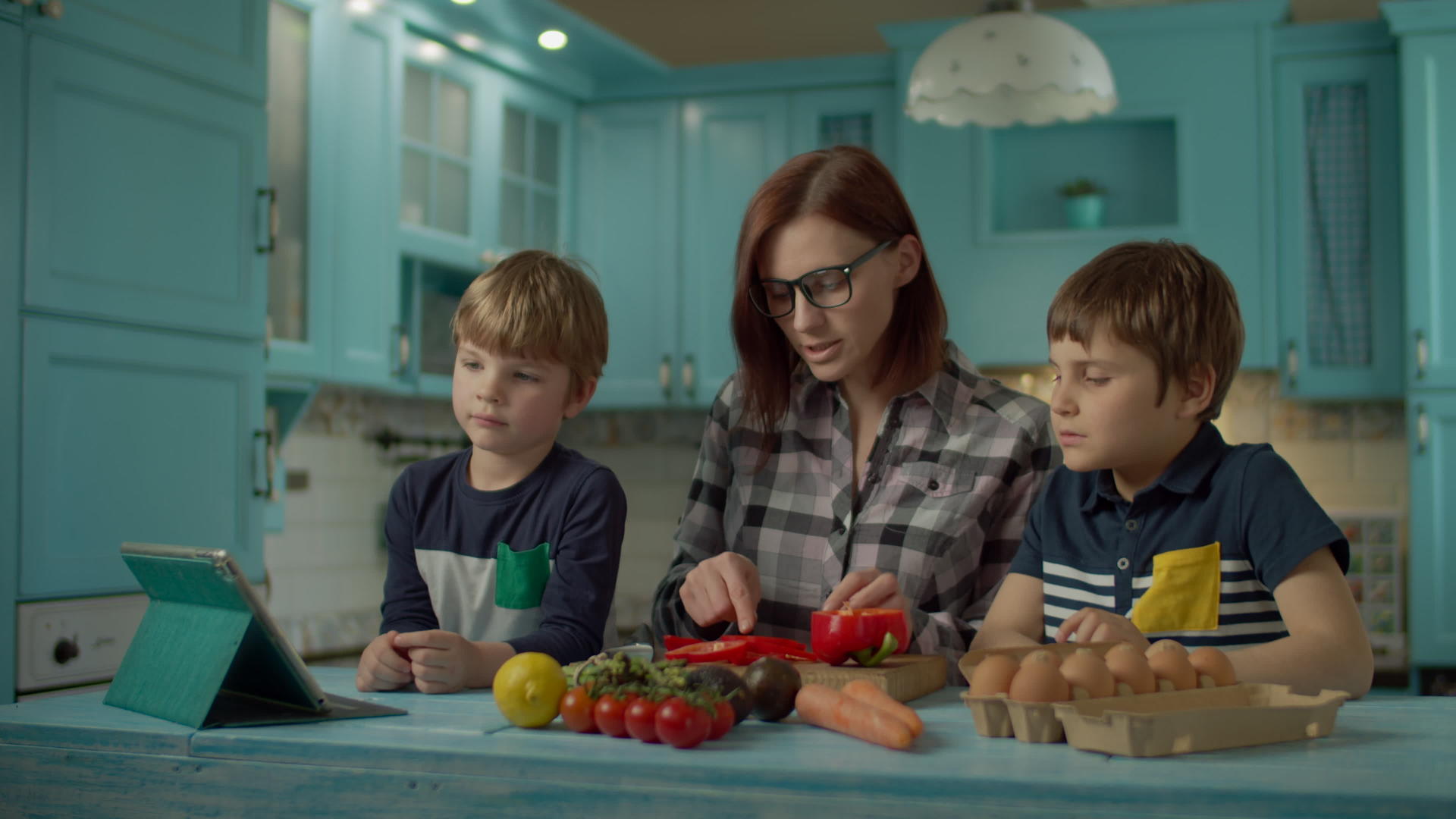 一家人一起做饭看着站在蓝色厨房的平板电脑上的在线食谱视频的预览图