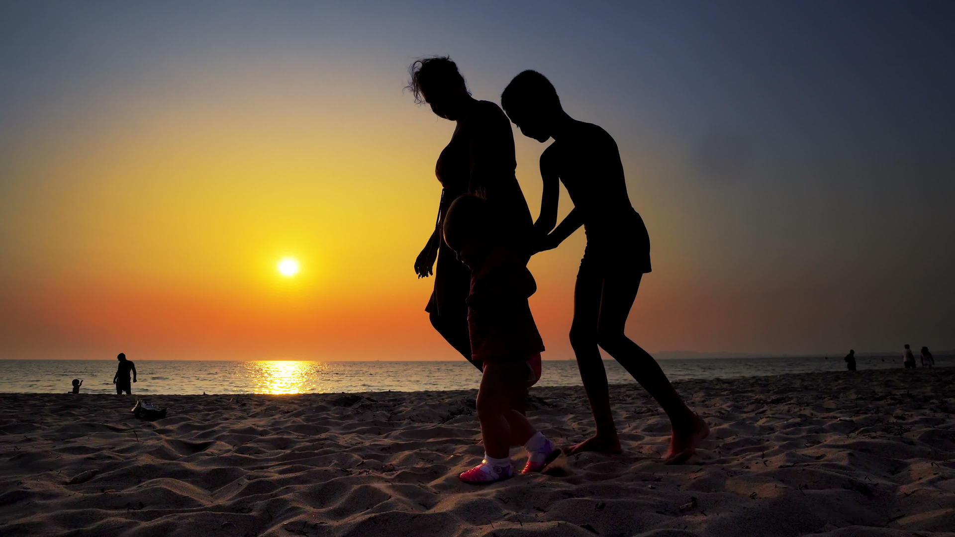 母亲和女儿在日落时在海滩上行走视频的预览图