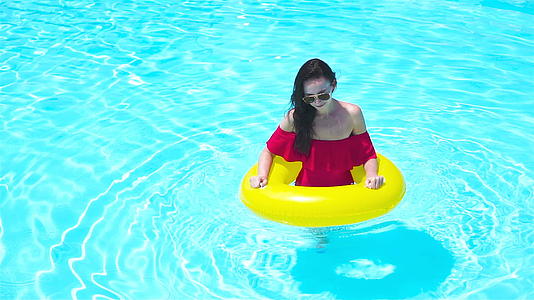 美丽的年轻女性在游泳池里放松豪华酒店并有一个充气的橡胶圈视频的预览图