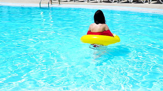 年轻美女在游泳池放松快乐女孩在豪华酒店的室外游泳池里视频的预览图
