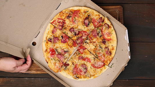 奶酪番茄香肠和蘑菇烤圆环披萨在白纸盒里切成碎片视频的预览图