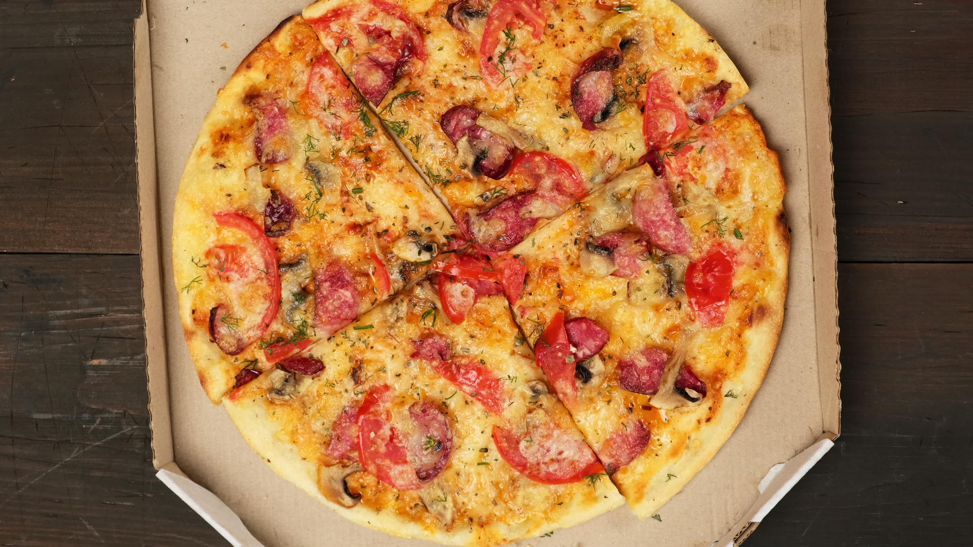 用香肠、西红柿和奶酪在白色纸板盒中烤成圆形披萨女人打开手视频的预览图