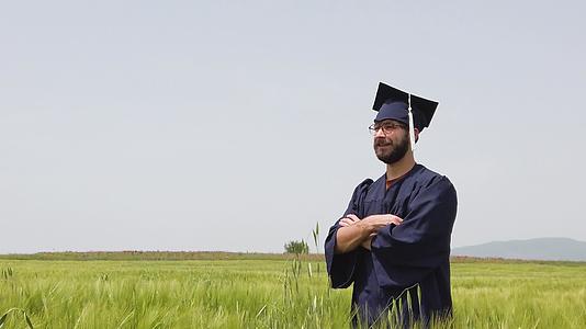 一个独自从绿地毕业的人把蓝色的帽子扔到空中视频的预览图
