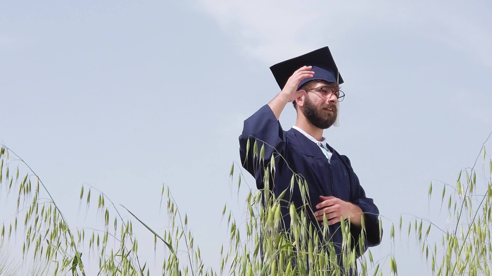 孤独的毕业男子在大自然中与蓝天对抗把蓝帽子扔在空中视频的预览图