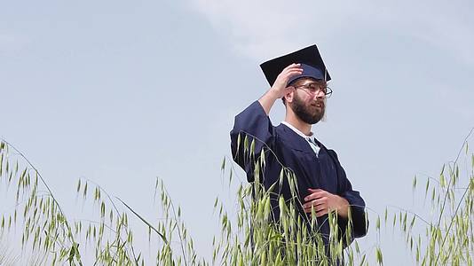 孤独的毕业男子在大自然中与蓝天对抗把蓝帽子扔在空中视频的预览图