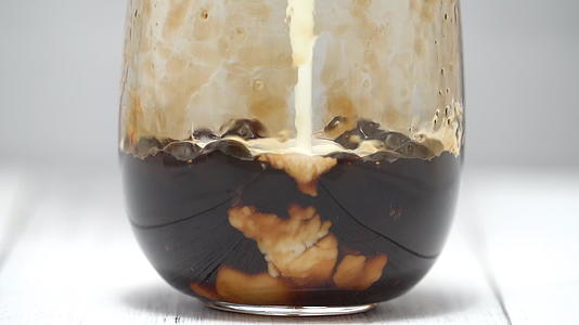 泡茶时将混合牛奶和茶倒入白色木桌背景上的红糖图案中视频的预览图