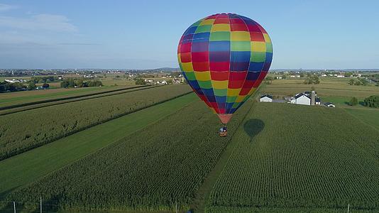 在农村阳光明媚的夏季节日期间热空气气球漂浮在农场上视频的预览图