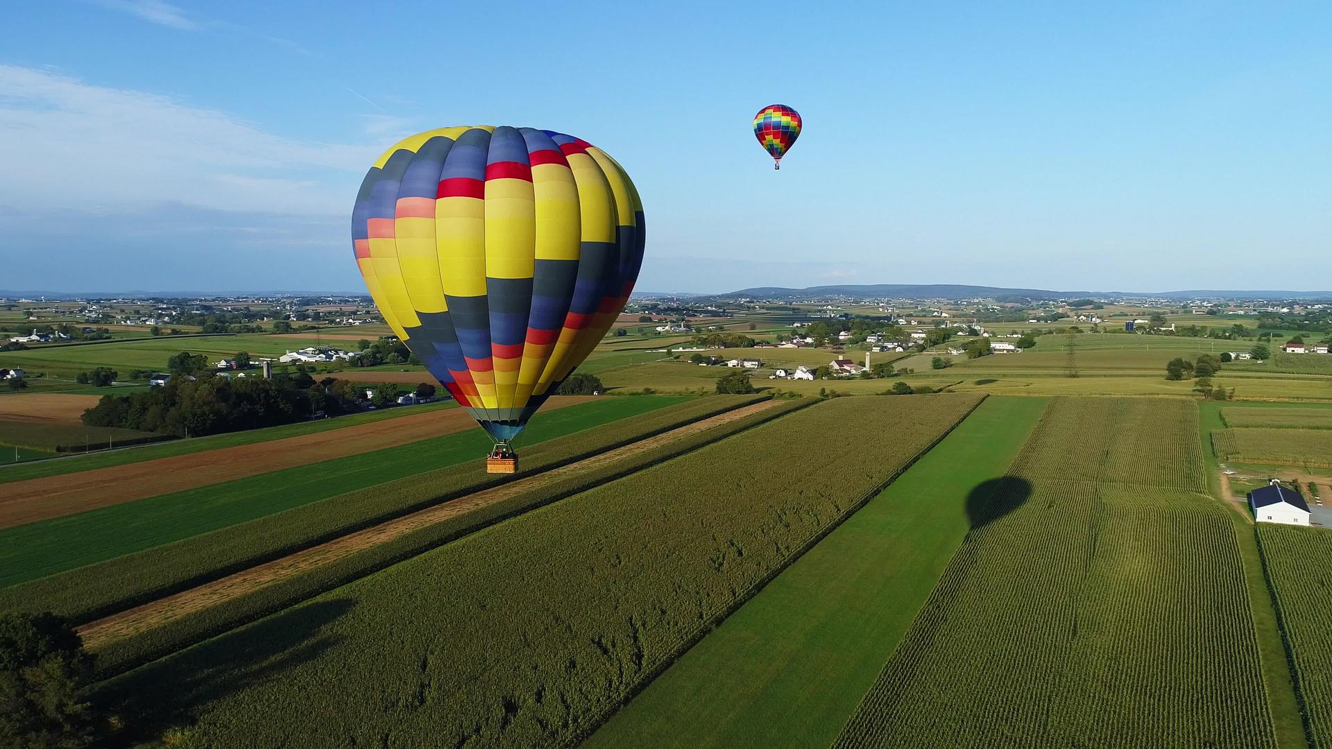 在阳光明媚的夏季庆典期间一个热空气气球漂浮在农场上视频的预览图
