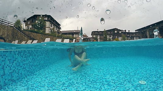 雨天雨滴打到水面时快乐的女孩享受游泳池gopro视频的预览图