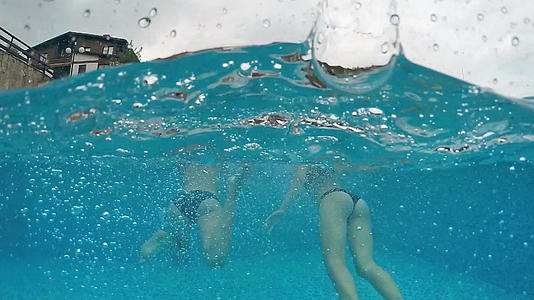 下雨天两个女孩冲进游泳池双腿喷在水面上视频的预览图
