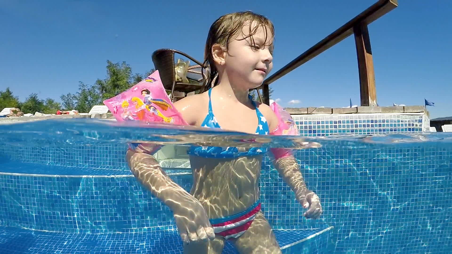 有臂带的小女孩享受户外温泉池的慢动作视频的预览图