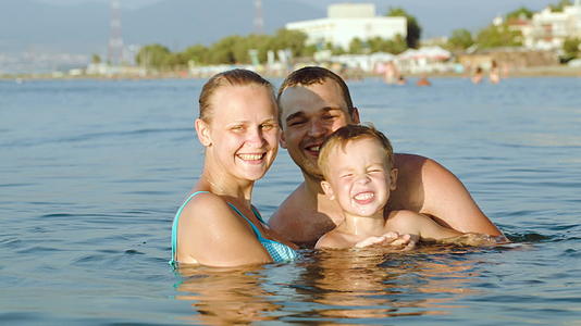 快乐的父母和儿子在海上洗澡视频的预览图