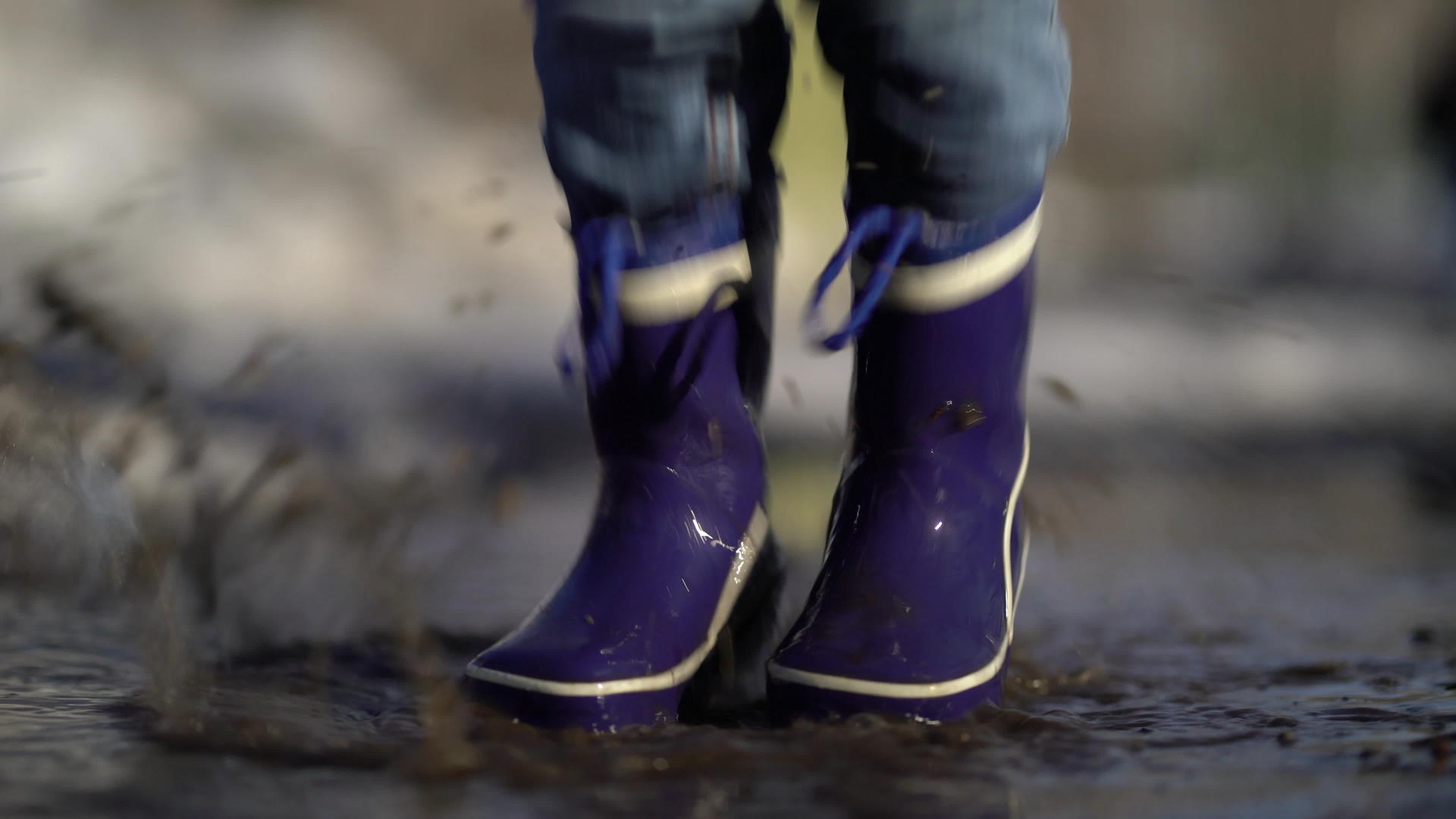 快乐的男孩橡皮靴在水坑和路上玩得开心视频的预览图