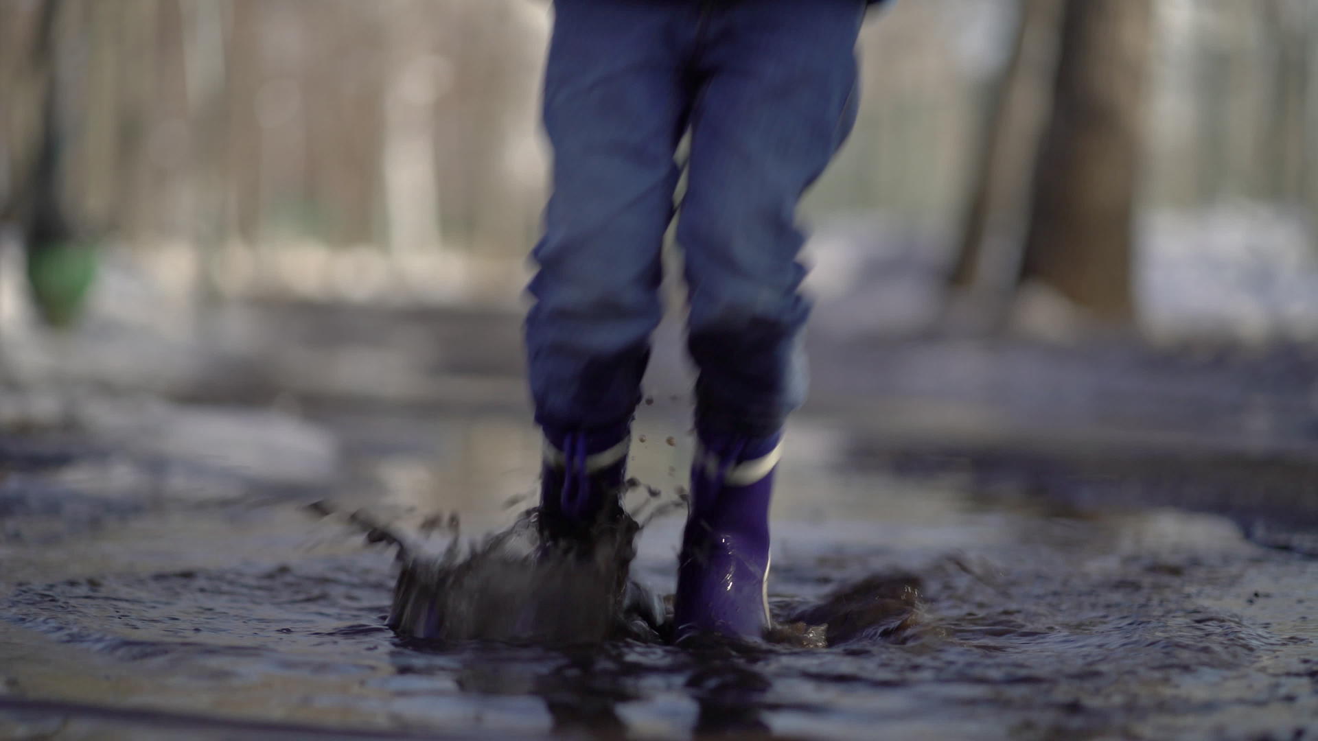 快乐的男孩橡皮靴在水坑和路上玩得开心视频的预览图