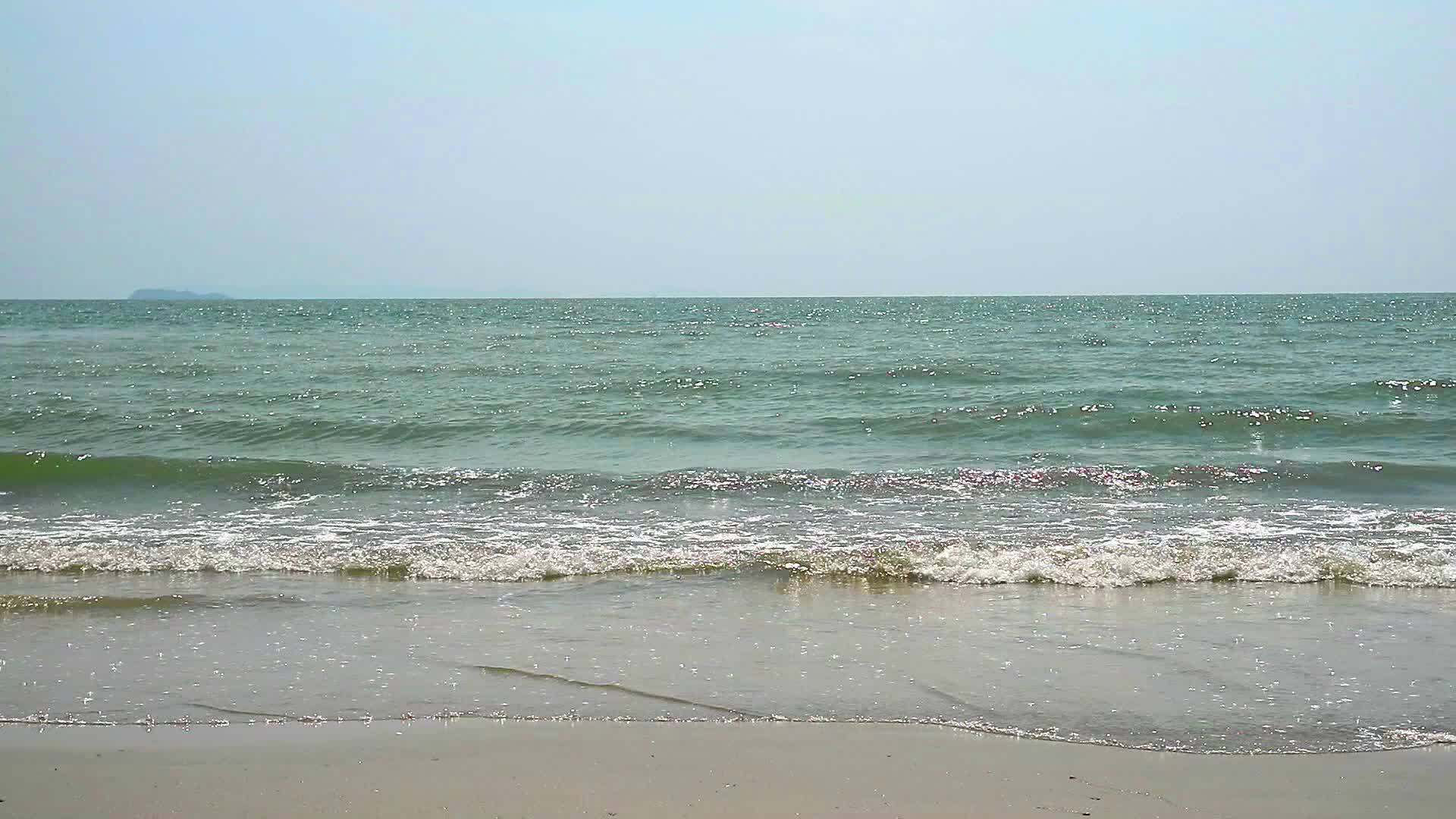 海滩上的小浪清澈的海水和水下的沙子以及模糊的背景视频的预览图