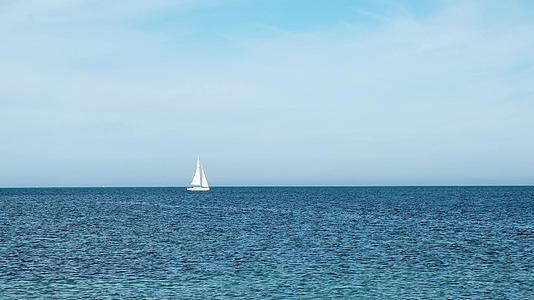 孤独的白色游艇漂浮在海平面的地平线上视频的预览图