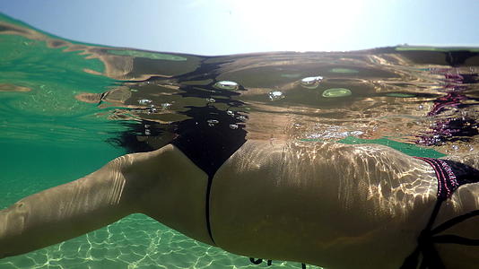 黑色卷发的女人穿着性感的泳衣漂浮在平静的水面上视频的预览图