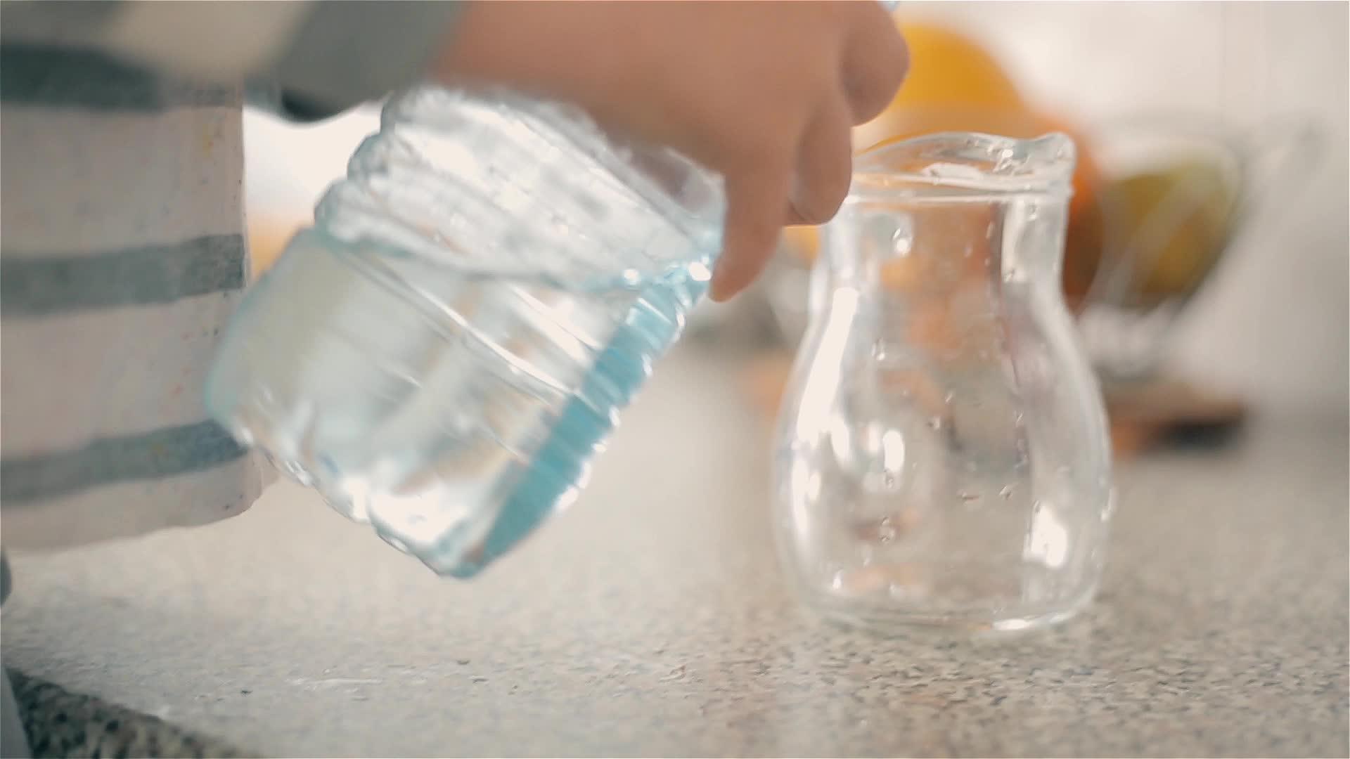 男孩从塑料瓶里倒了一壶干净的饮用水视频的预览图