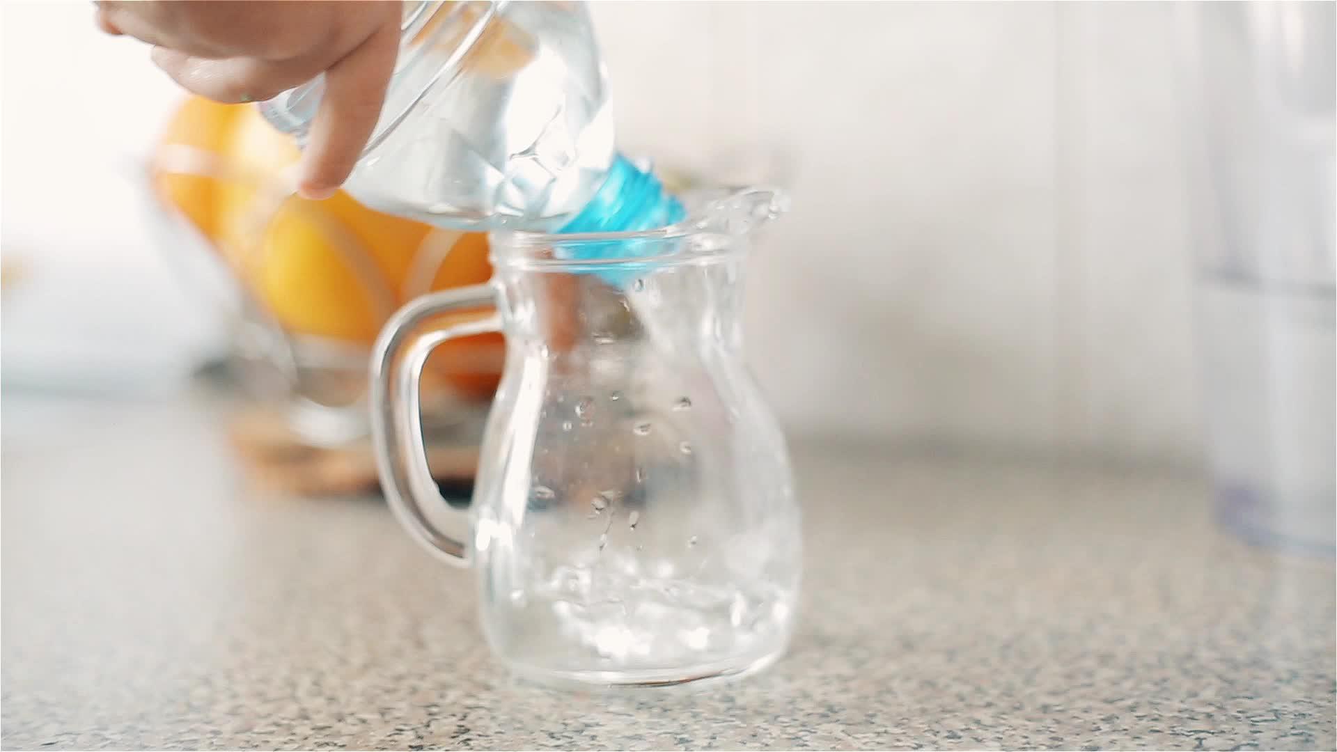 一个孩子从塑料瓶里倒了一壶干净的饮用水视频的预览图