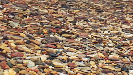 清澈透明的暖水在海边或湖边有五颜六色的石头视频的预览图