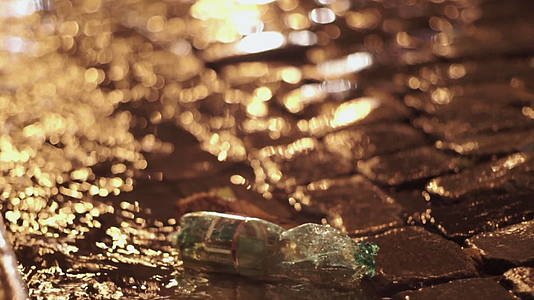 晚上在老城区可白石街污染的重雨中塑料瓶在大水坑里视频的预览图