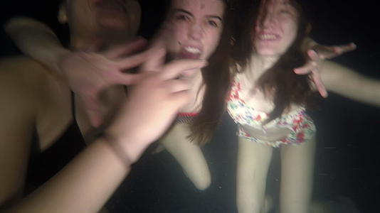 三个女孩的朋友在暗泳池里玩得很开心视频的预览图