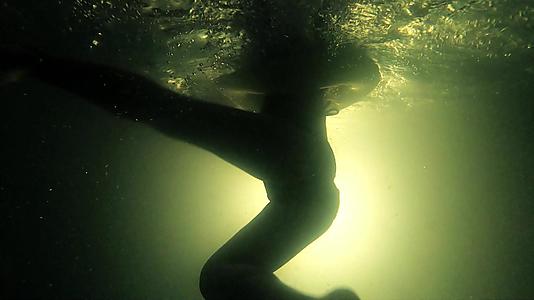 一个孩子带着充气环在黑暗肮脏的游泳池里游到水底视频的预览图