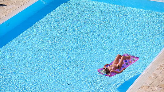 年轻女性在大游泳池的比基尼空气床垫中视频的预览图
