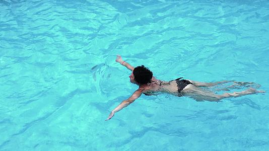 一个年轻的女人色泳衣在游泳池游泳视频的预览图