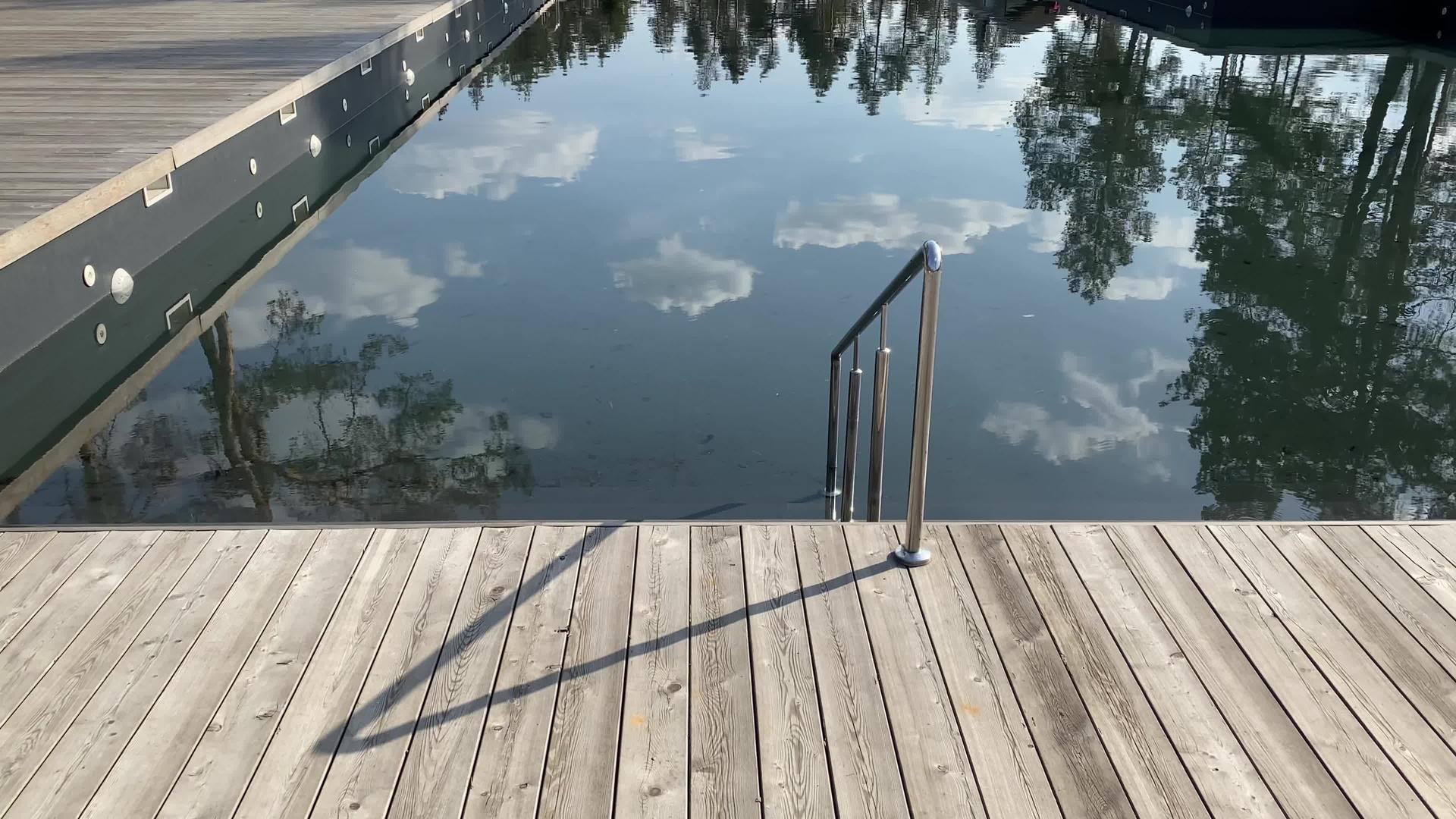 一个阳光明媚的日子在松树林的游泳池旁边的木制甲板上视频的预览图