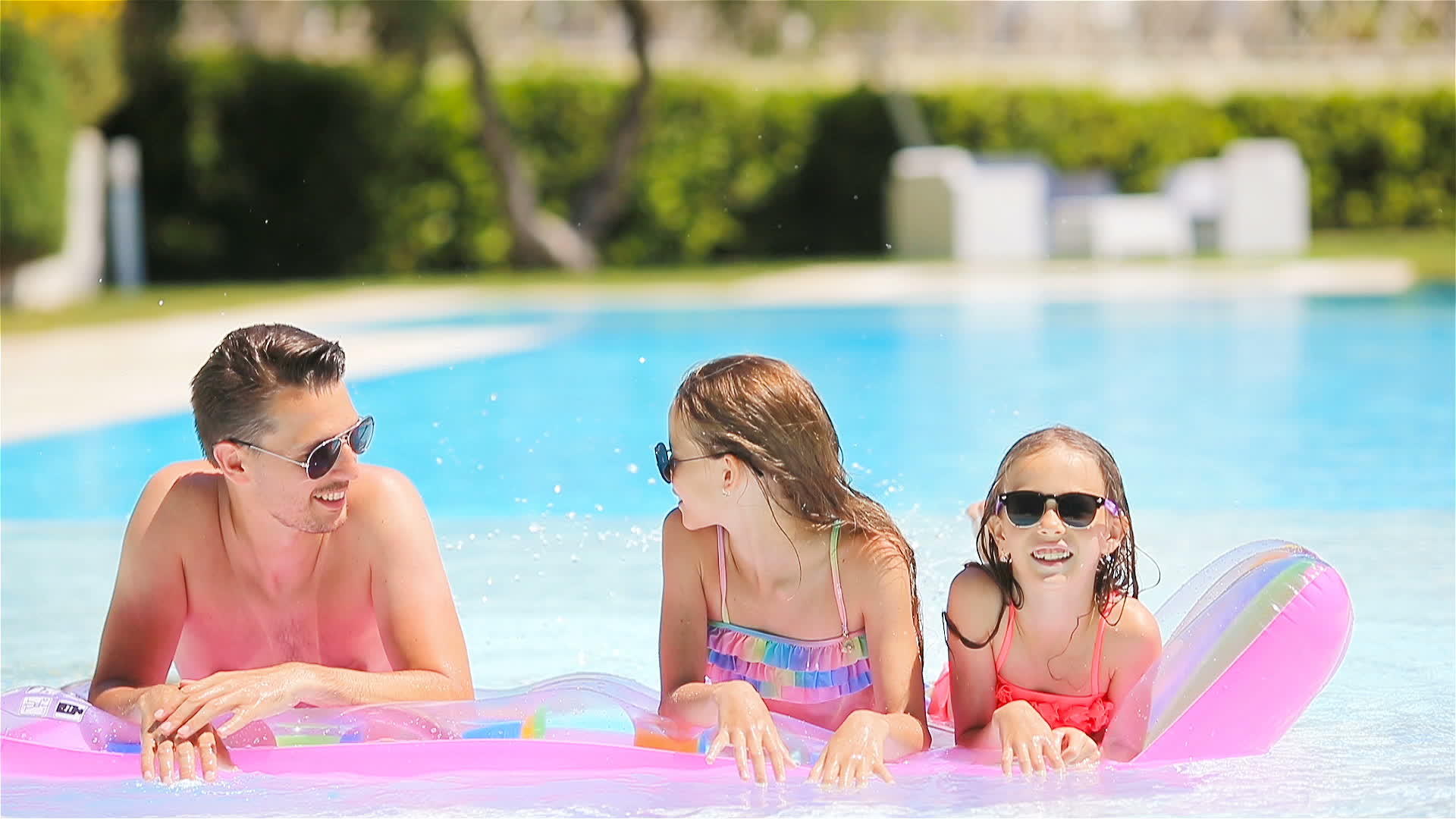 父亲和两个孩子在豪华的游泳池里度暑假视频的预览图