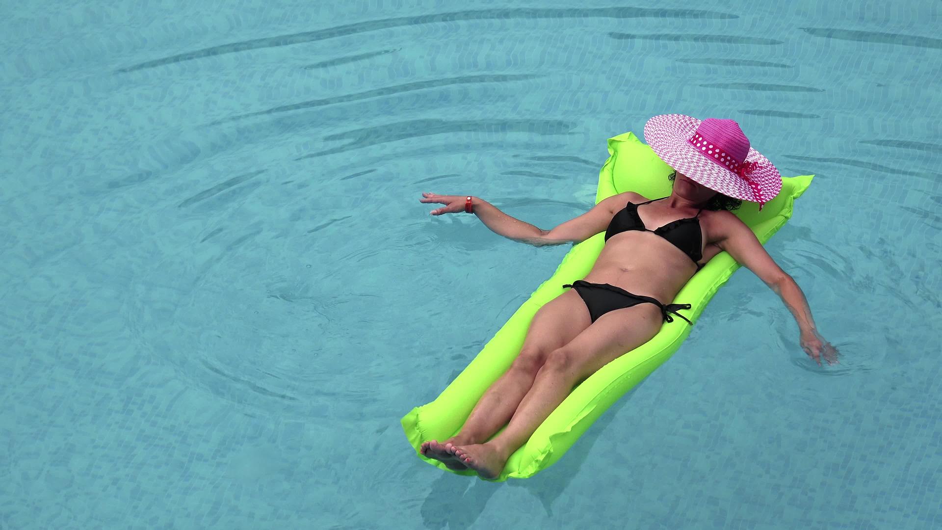 在大游泳池的绿色气垫上穿比基尼享受晒黑假期的概念视频的预览图