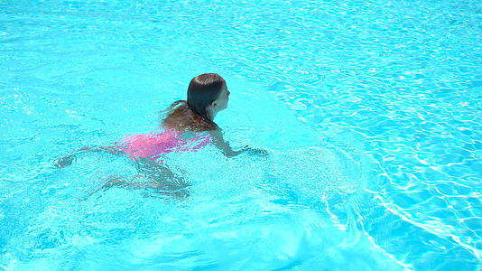 可爱的小女孩在户外游泳池游泳视频的预览图
