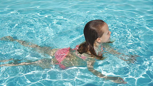 可爱美丽的小女孩在户外游泳池游泳视频的预览图