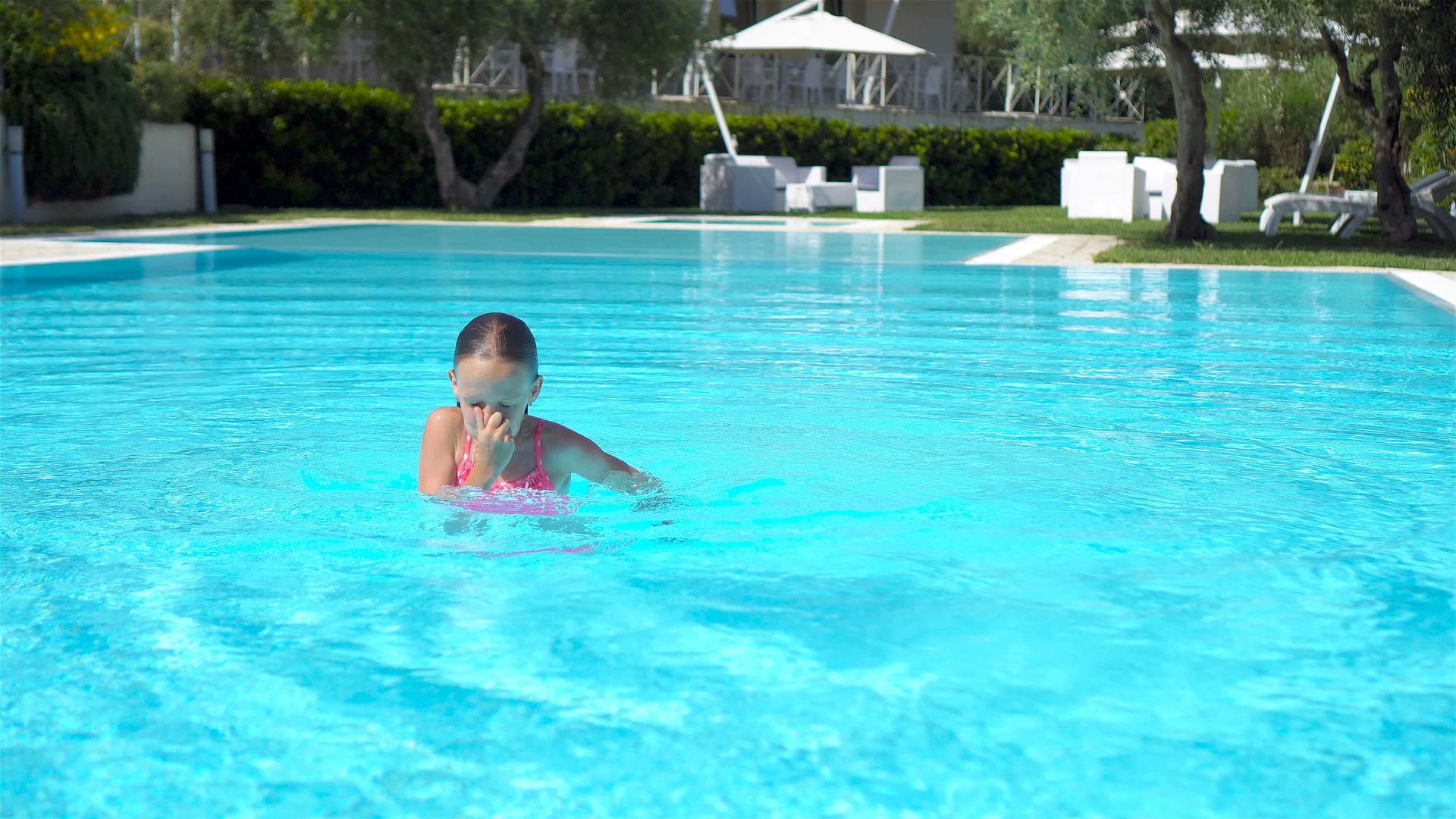 可爱的小女孩在户外游泳池游泳视频的预览图