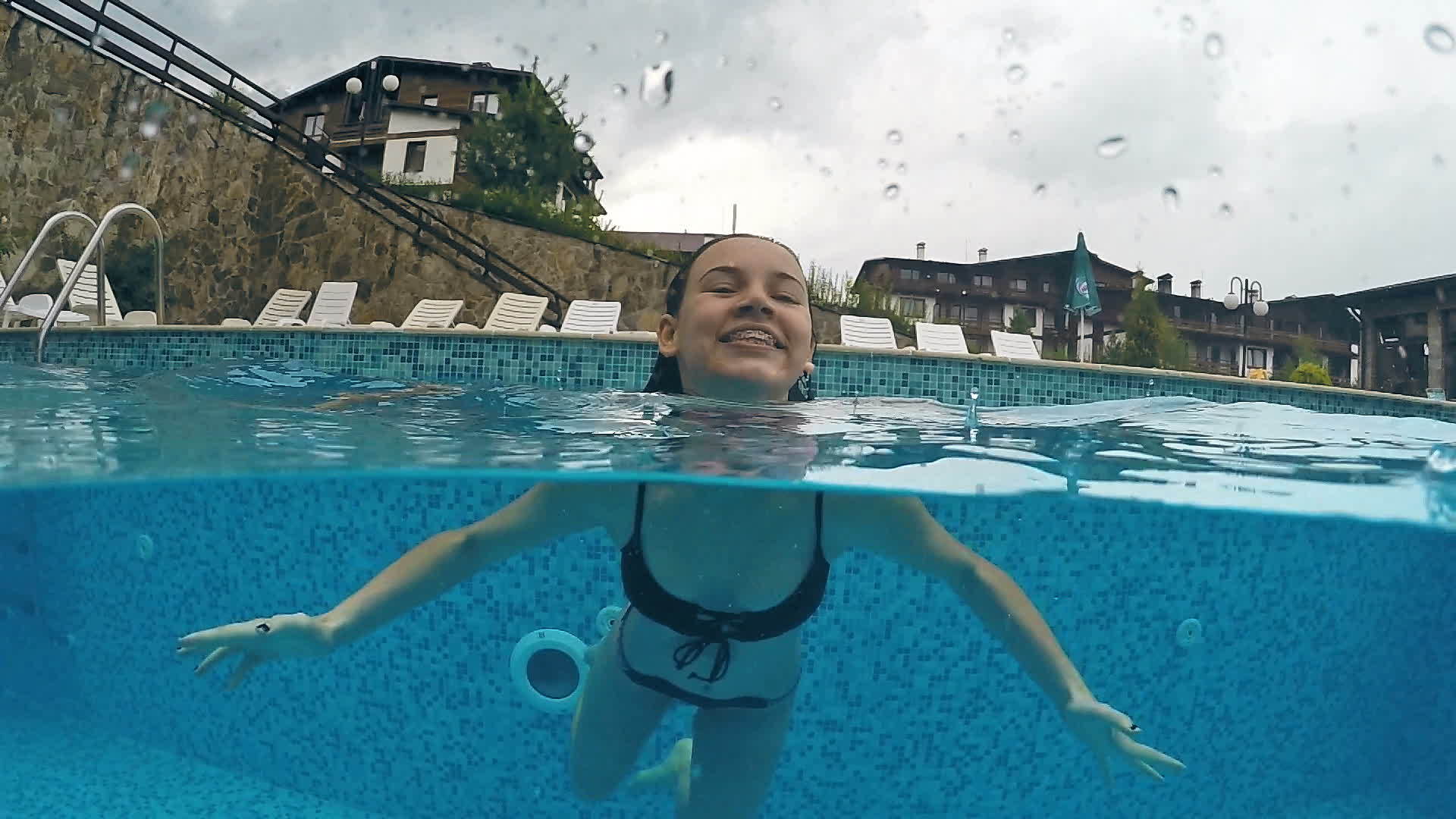 雨天在游泳池里游泳时戴着牙套的女孩微笑着gopro穹顶视频的预览图