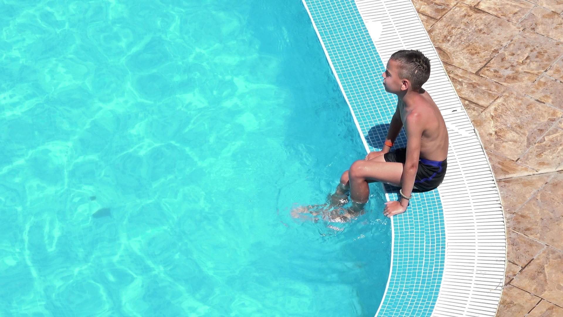 英俊的男孩在泳池前台玩了四公里保持双腿在水中保持新鲜视频的预览图