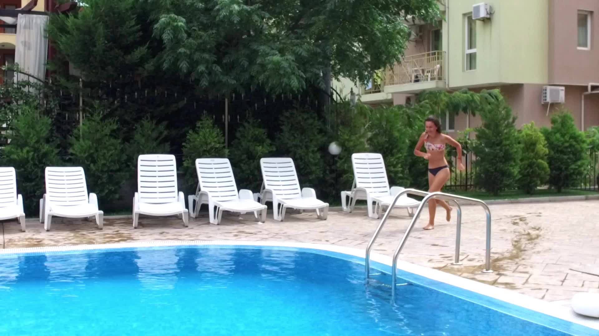 女孩在蓝色游泳池里跑步、跳跃、慢动作视频的预览图