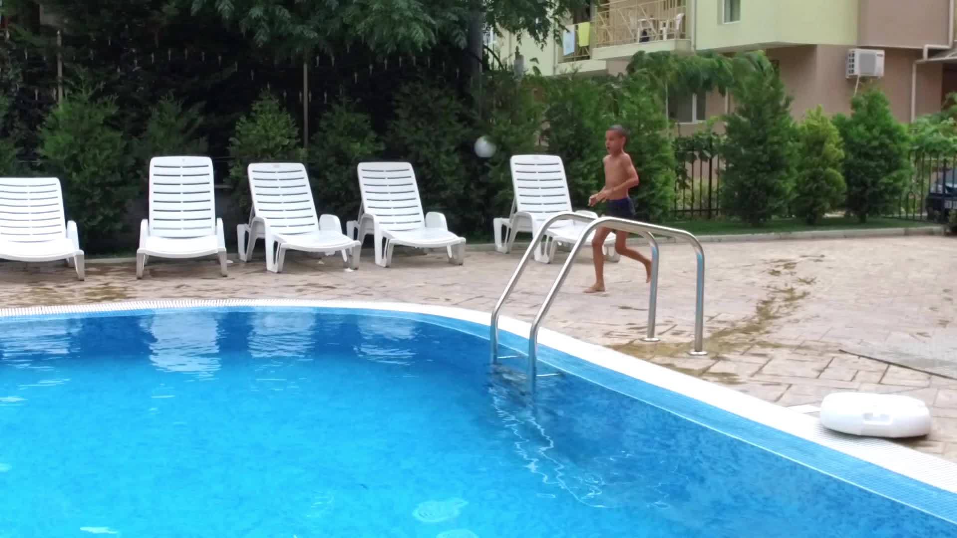 男孩在蓝色游泳池里跑步、跳跃、慢动作视频的预览图
