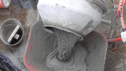 混凝土搅拌机将湿水泥倒入独轮车电动混凝土搅拌机中视频的预览图