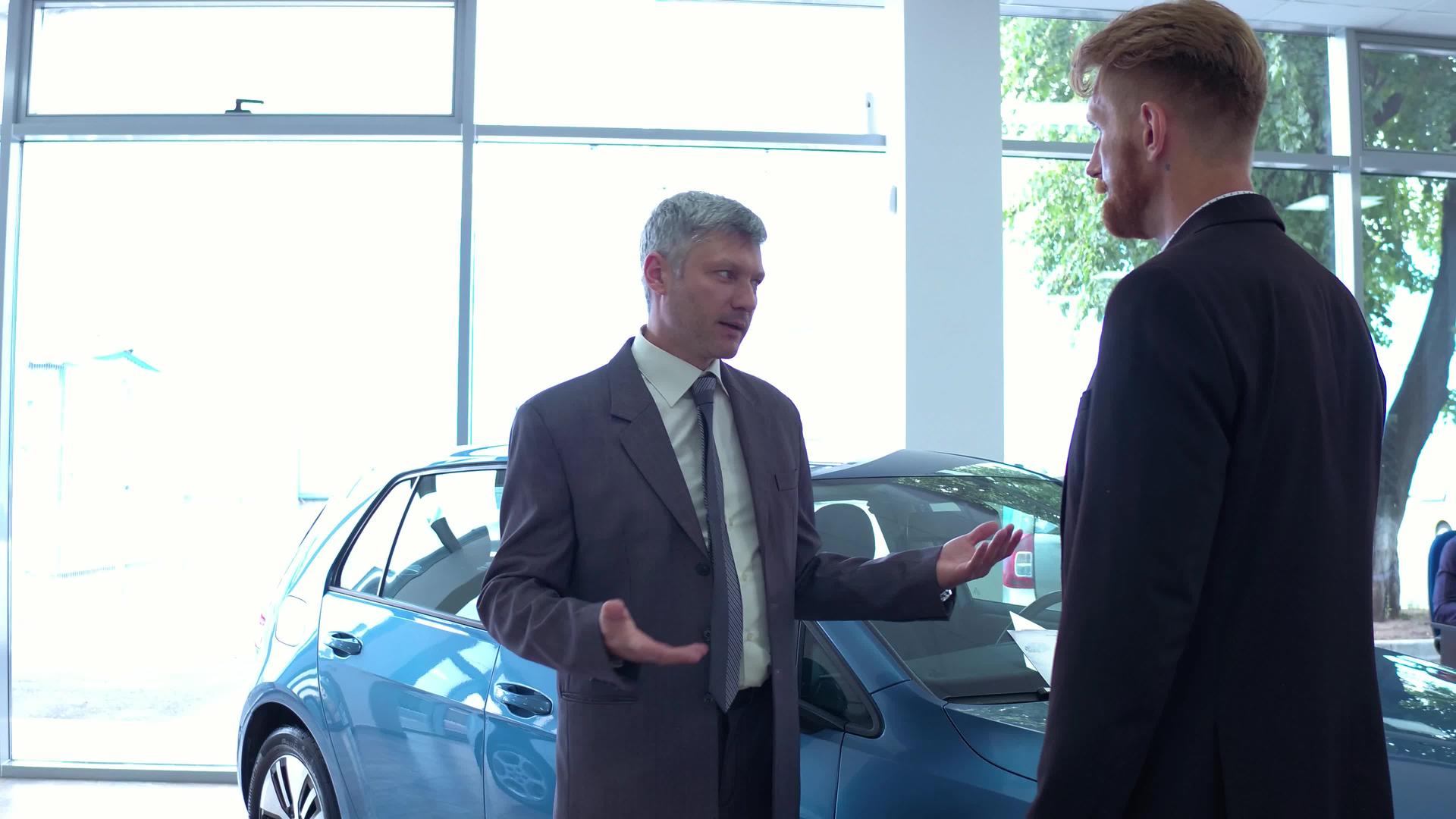汽车展厅的帅哥和汽车经销商谈话视频的预览图